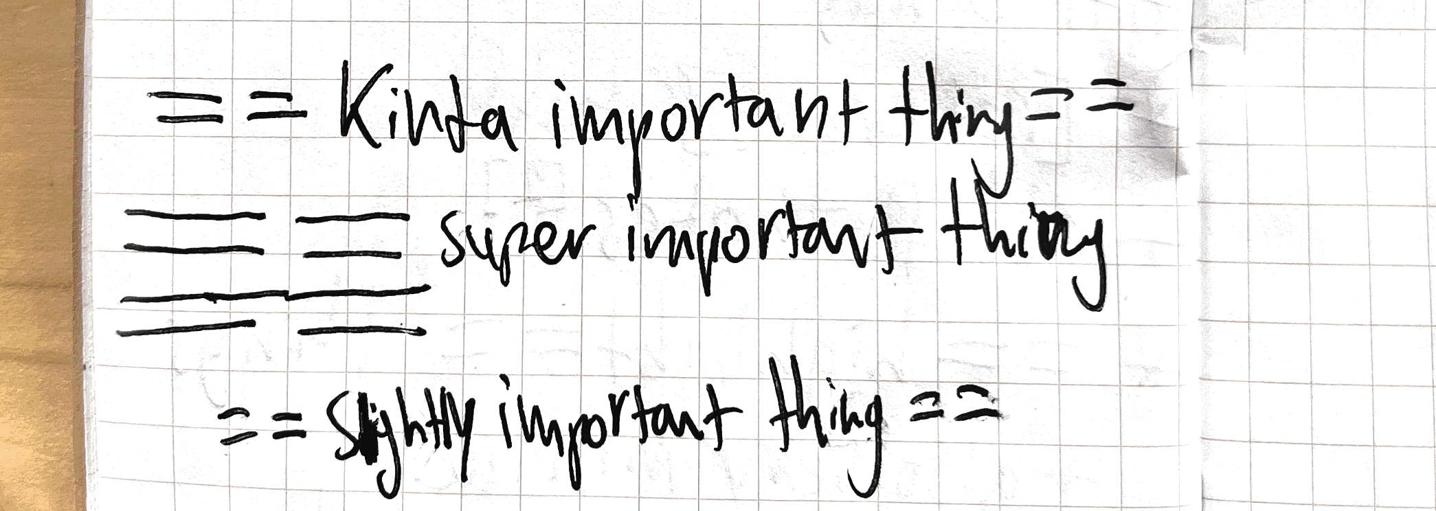 Highlighting Close-up photo of a handwritten note on grid paper demonstrating the use of varying widths of equal signs on either end of ideas for varying emphasis